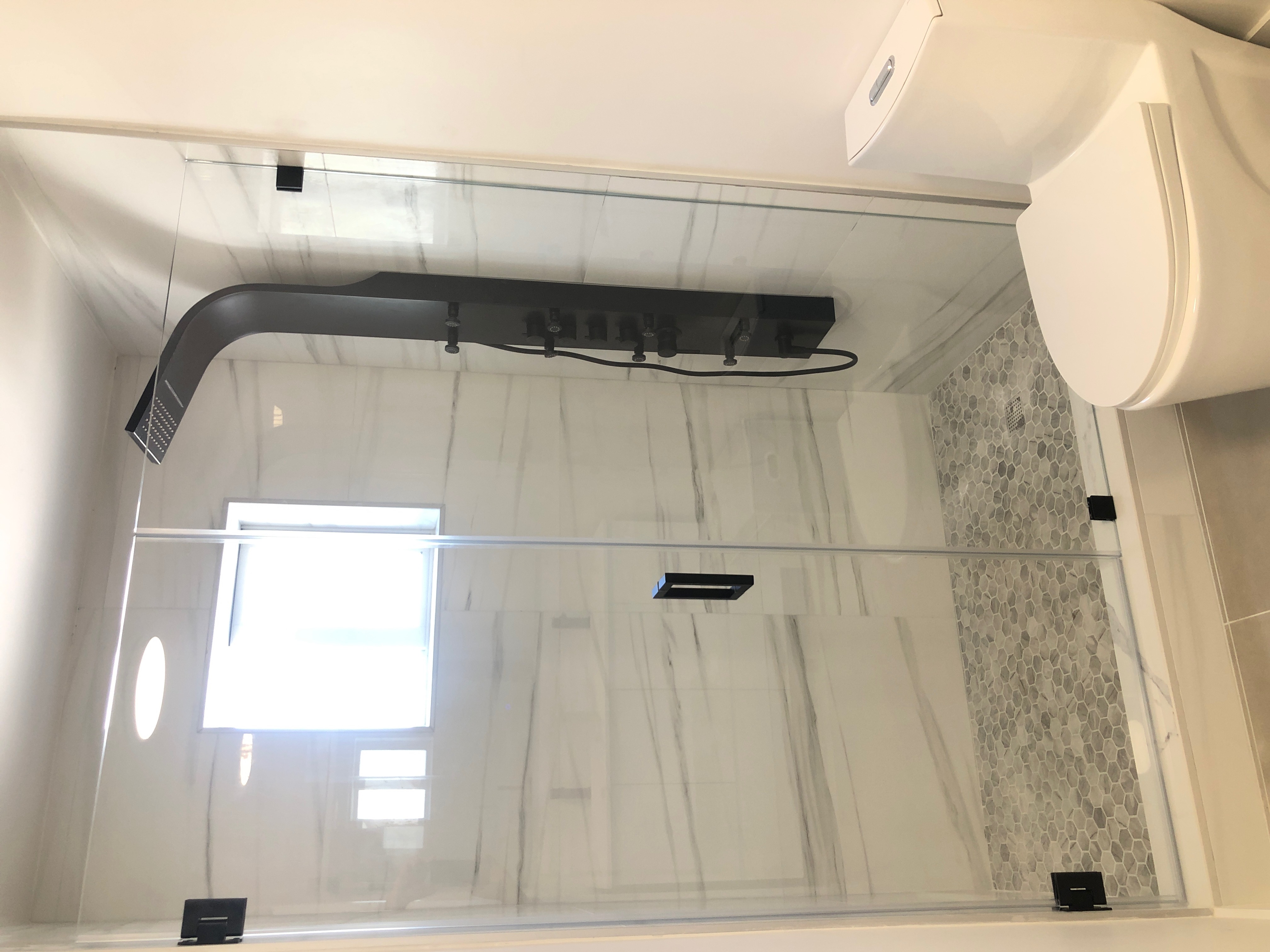 A Porcelain Marble Modern Bathroom Remodel with Black Accents by Anchor Construction